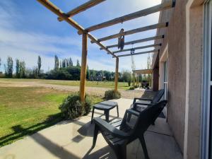 een patio met 2 stoelen, een tafel en een pergola bij Finca Los Racimos - Casa Syrah in San Rafael