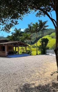 a pavilion with palm trees and a hill in the background at Sítio com piscina incrível in Santo Amaro da Imperatriz