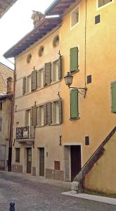 an old building with green shutters on a street at Albergo Diffuso Polcenigo Ca' Bianca in Polcenigo