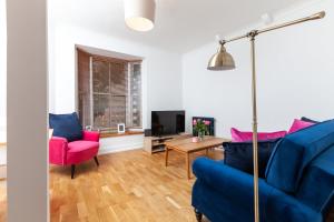 a living room with a blue couch and pink chairs at GuestReady - Uma joia escondida em Brighton in Brighton & Hove