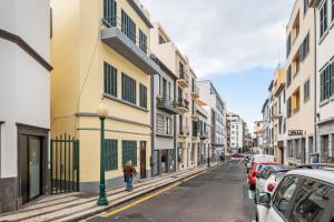 a street with buildings and a person walking down the street at Ponte Nova Studios in Funchal