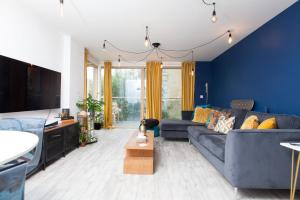 uma sala de estar com paredes azuis e um sofá azul em GuestReady - Lush moderno perto do Queen's Park em Brighton & Hove