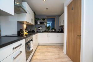 uma cozinha com armários brancos e bancadas pretas em GuestReady - Lush moderno perto do Queen's Park em Brighton & Hove