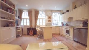 a large kitchen with white cabinets and a table at Spacious luxury central London 1-bed apartment in London