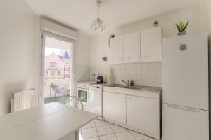 a kitchen with white cabinets and a white refrigerator at Fonctionnel et Calme avec parking gratuit in Villeurbanne