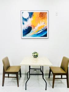 une table avec deux chaises et un tableau sur le mur dans l'établissement Tina Homestay 2 Đà Nẵng, à Đà Nẵng