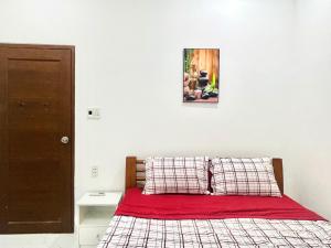 Cette chambre comprend un lit avec des draps rouges et une photo murale. dans l'établissement Tina Homestay 2 Đà Nẵng, à Đà Nẵng