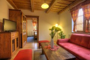 a living room with a red couch and a table at Penzión Grobský Dvor in Slovenský Grob