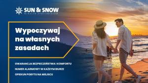 ein Paar, das bei Sonnenuntergang am Strand spazieren geht in der Unterkunft Solny Resort, Sun & Snow in Kołobrzeg