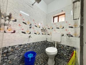 a bathroom with a toilet and some flowers on the wall at Hornbill inn in Cochin