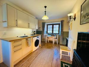 een keuken met een wastafel en een wasmachine. bij Rosemount Cottage ONE- Highland Cottage in Garve