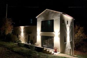 a white house with lights on the side of it at night at Maison Spacieuse situation idéale au calme in Bouillac