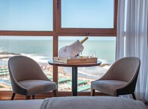 マル・デル・プラタにあるHOTEL KONKE MAR DEL PLATAの椅子2脚、テーブル、シャンパン1本が備わる客室です。