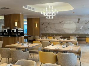 a restaurant with tables and chairs and a chandelier at Hotel Marina Port in Balatonkenese