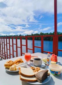a table with a plate of food and a view of the water at Hotel Beira Rio Preguiças in Barreirinhas