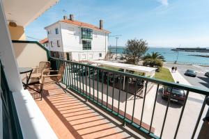 Il dispose d'un balcon avec une maison blanche et l'océan. dans l'établissement Vila Sen Vento - Aguiño, à Ribeira