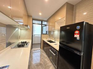 een keuken met een zwarte koelkast en een wastafel bij R&F Princess Cove 3-1 DS Homestay 民宿 in Johor Bahru