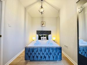 a bedroom with a large blue bed with two lamps at LakeDistrict Sweetness by Sleepy in Millom