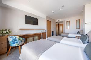 una camera d'albergo con due letti e una televisione di HOTEL KONKE MAR DEL PLATA a Mar del Plata