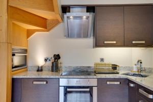 una cocina con electrodomésticos de acero inoxidable y armarios de madera en South Stable at Hallsteads: Cosy Stone Cottage, with Parking en Alnmouth