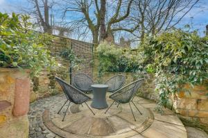 a patio with four chairs and a table and a wall at South Stable at Hallsteads: Cosy Stone Cottage, with Parking in Alnmouth