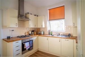 a kitchen with white cabinets and a stove top oven at GuestReady - Kemptown Coastal Comfort in Brighton & Hove