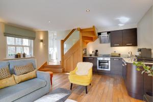 a living room with a couch and a kitchen at South Stable at Hallsteads: Cosy Stone Cottage, with Parking in Alnmouth