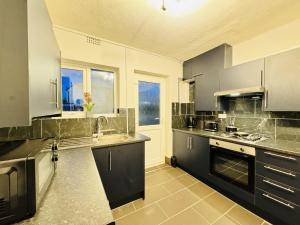 a large kitchen with black cabinets and a sink at LakeDistrict Vacation Time by Sleepy in Millom