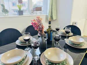 a table with plates and wine glasses and a bottle of wine at LakeDistrict Vacation Time by Sleepy in Millom