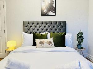 um quarto com uma grande cama branca com almofadas verdes em LakeDistrict Vacation Time by Sleepy em Millom