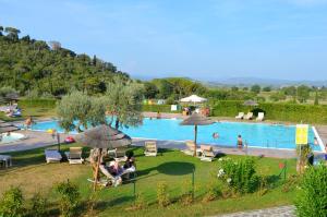 a swimming pool with people sitting in chairs and umbrellas at Le Corti Di Montepitti in Suvereto