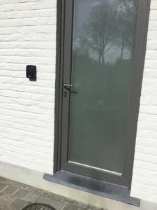 a glass door with a reflection of a tree at Gezellige Studio met terras in Oudenaarde