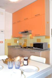 ビビオーネにあるLionのキッチン(オレンジ色のキャビネット、カウンタートップ付)