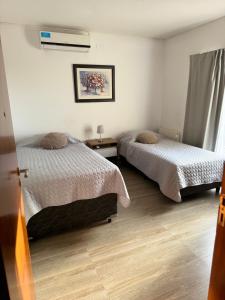 1 dormitorio con 2 camas y una lámpara en el suelo de madera en Mendoza Casa Barrio Cerrado en Chacras de Coria