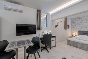 a bedroom with a bed and a desk and chairs at Paleo Faliro Gardenbay in Athens