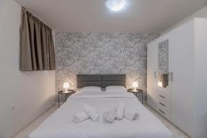 a bedroom with a large white bed with two lamps at Paleo Faliro Gardenbay in Athens
