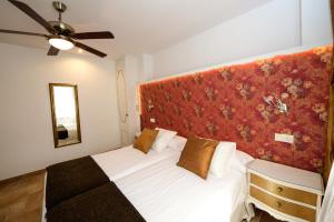 1 dormitorio con cama blanca y pared roja en El Canton De Carlos en Castelserás