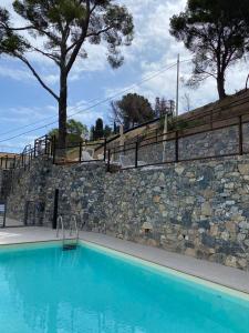 a large blue swimming pool next to a stone wall at Luxury Blue Paradise Alassio in Alassio