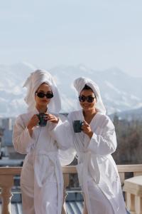 two women dressed in white drinking from coffee cups at Hotel 28 in Bishkek
