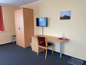 a room with a desk with a chair and a television at Pension Leyerhof in Wendisch Baggendorf