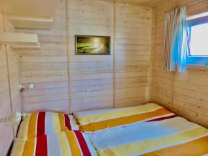 um quarto com 2 camas num quarto de madeira em Hausboot Lilla Lina em Fehmarn