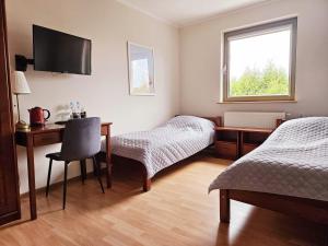 a room with two beds and a desk and a television at Restauracja Hotel Przystan in Lublin