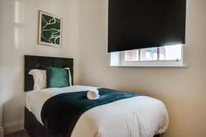 Lovely 1-Bed Apartment in Wigan في ويغان: غرفة نوم فيها سرير مع قطه جالسه عليه