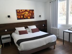 a bedroom with a bed with a painting on the wall at Logis Hôtel-Restaurant Le Tanargue in Valgorge +29 photos