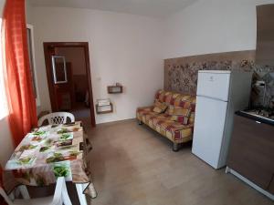 ein Wohnzimmer mit einem Tisch und einem Kühlschrank in der Unterkunft CAROSELLO in Torre San Giovanni Ugento