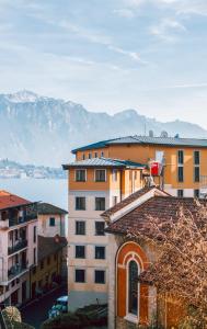 un grupo de edificios con montañas en el fondo en Authentic Italian Home, en Cadenabbia