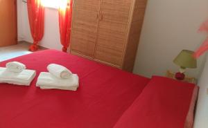 ein rotes Bett mit zwei Handtüchern darüber in der Unterkunft CAROSELLO in Torre San Giovanni Ugento