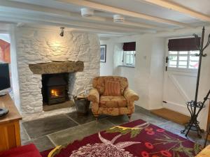 a living room with a stone fireplace and a chair at Chapel Annex in Bodmin