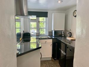 a kitchen with white cabinets and a black counter top at Chapel Annex in Bodmin +10 photos