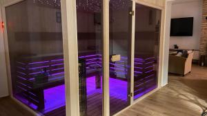 Puerta de cristal con luces moradas en la sala de estar en Kukorica Csárda Apartman, en Balatonújlak